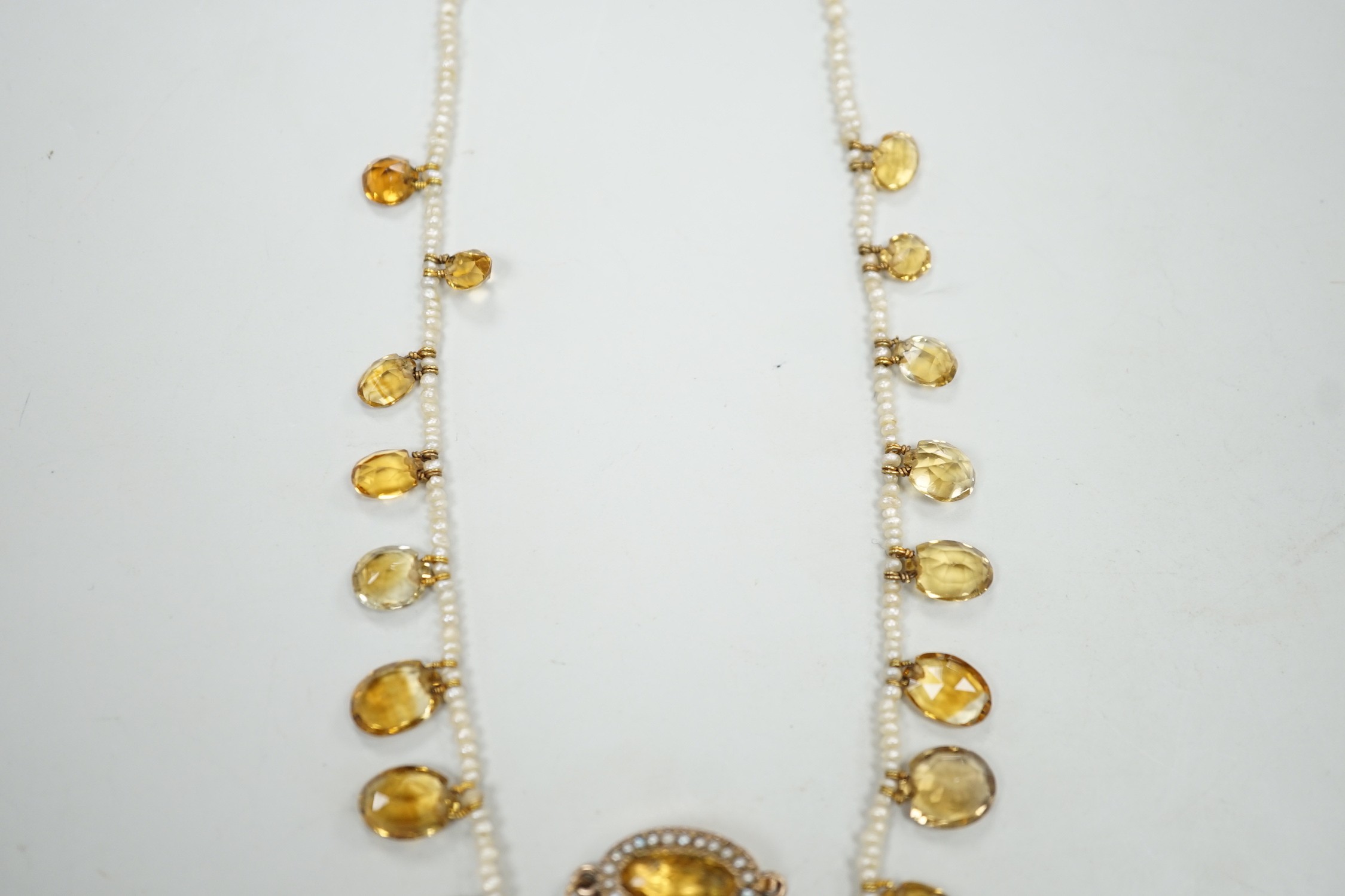 An Edwardian twenty one graduated oval cut citrine set seed pearl necklace (a.f) clasp loose, approx. 34cm.